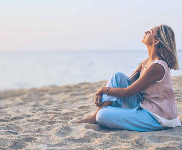 Frau bei Sonnenuntergang am Meer mit Notizbuch im Arm – Sinnbild für Selbstfindung, Loslassen und innere Ruhe